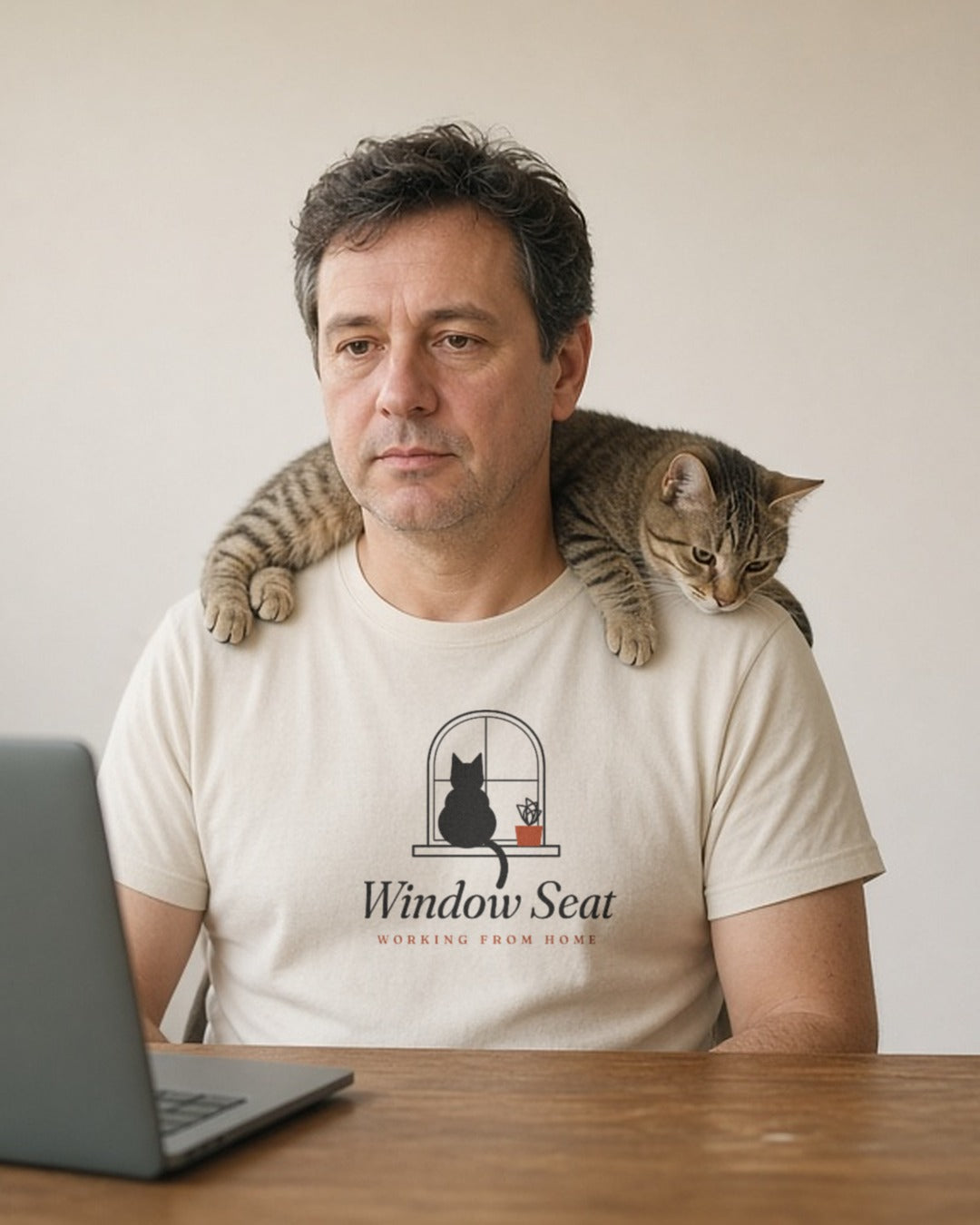 The Window Seat Tee in Ivory, a man (40s) on a video call, a cat walking across his shoulders