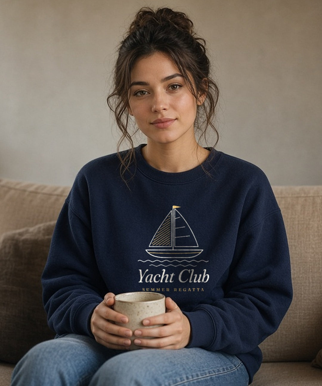 The Yacht Club Crewneck in Navy, woman on a linen sofa at home, mug held in her lap, window light