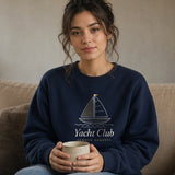 The Yacht Club Crewneck in Navy, woman on a linen sofa at home, mug held in her lap, window light