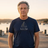 The Yacht Club Tee in True Navy, man standing on a wooden dock at sunset, hands in his pockets